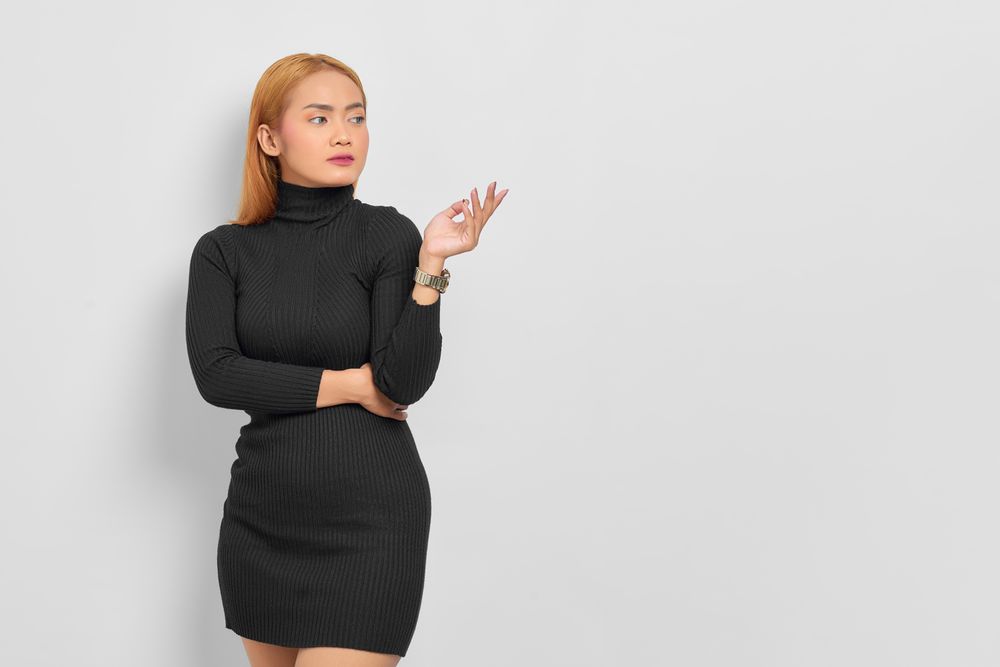 Sultry Asian woman with red hair in dark dress in studio shoot with copy space