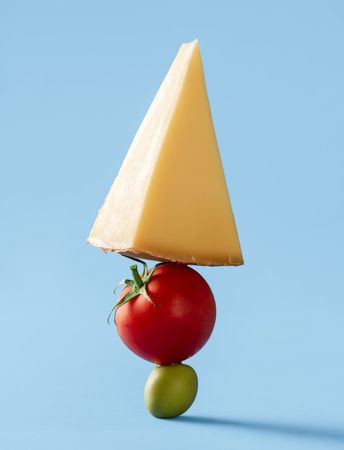 Swiss cheese with tomato and green olive isolated on blue background