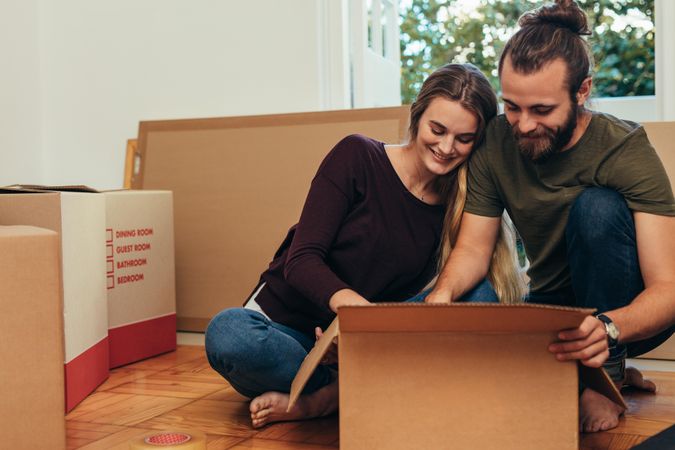 Couple sitting together on floor unpacking their boxes