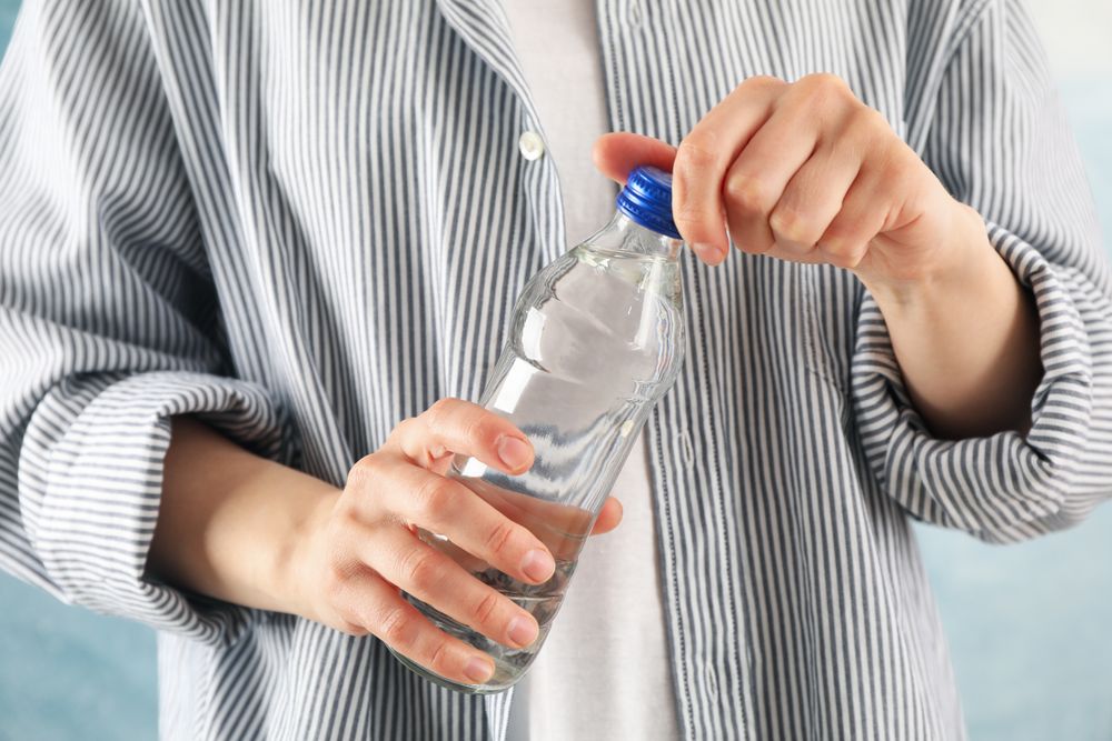 Torso of person opening a plastic water bottle