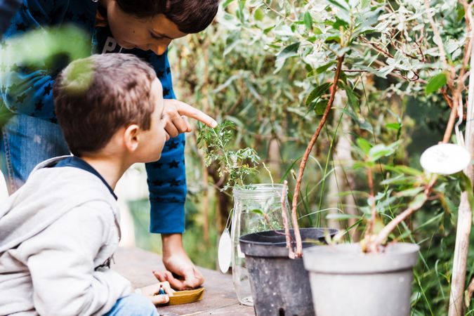 Person pointing at plant in can near child
