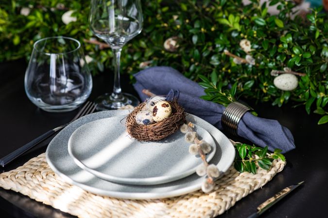 Easter table setting with eggs in nest on plate with natural light