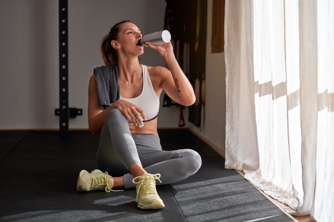 Fit woman drinking water after training