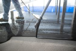 Crop unrecognizable people pouring concrete on floor