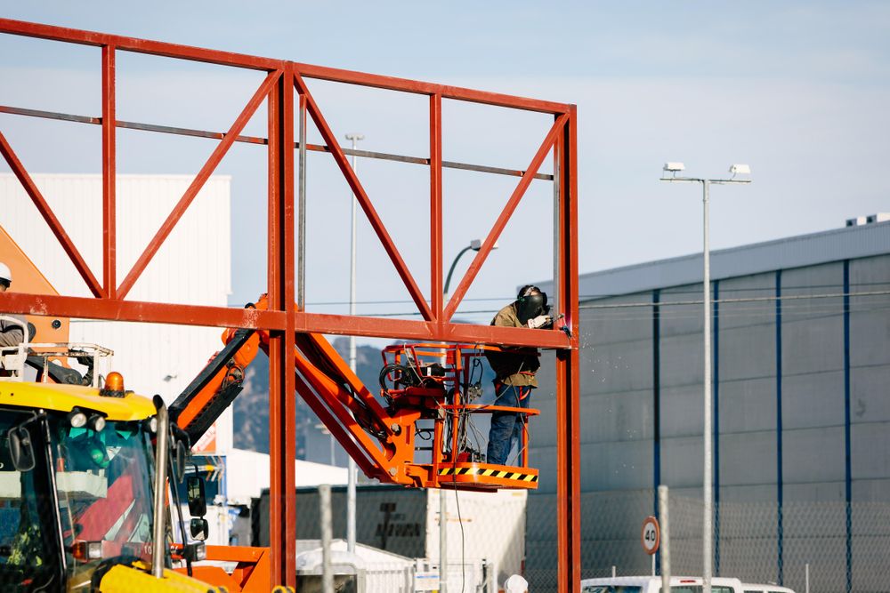 Man welding a billboard frame above a building