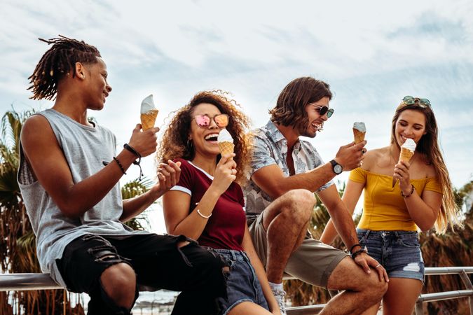 Smiling young men and women eating ice-cream outdoors
