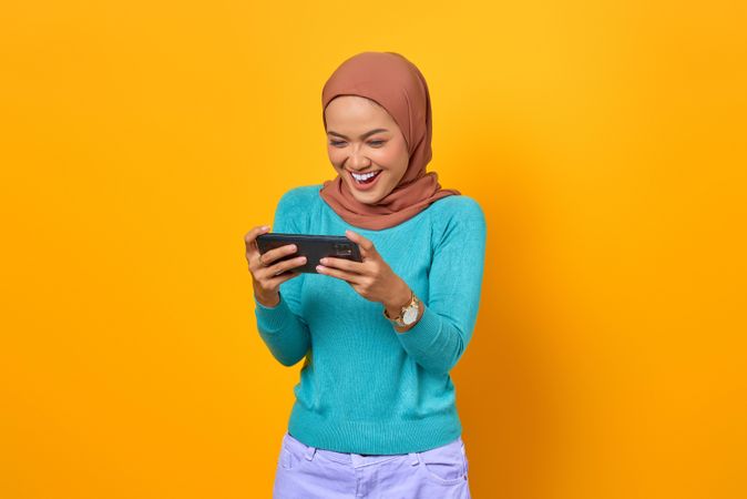 Happy Muslim woman looking at her smartphone