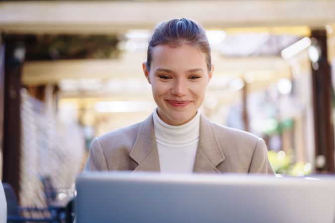 A Smiling Woman Working Efficiently on Her Laptop While Enjoying a Beautiful Outdoor Setting