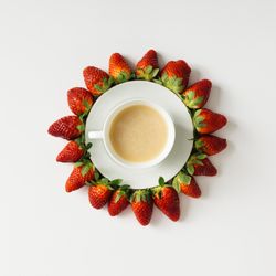 Coffee and saucer surrounded with strawberries