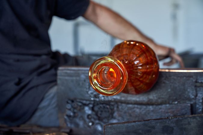 Crop man forming vase from glass