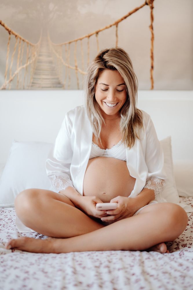 Smiling pregnant woman using smartphone at home