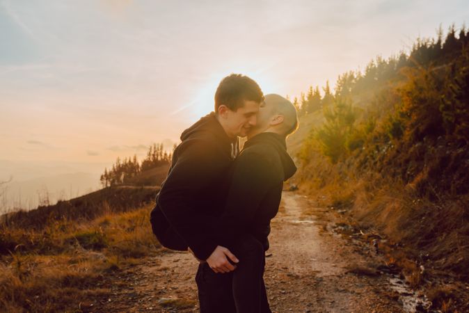 Men hugging and kissing in forest