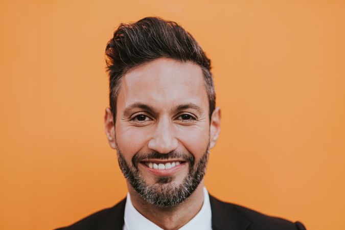 Adult stylish man in costume near orange wall