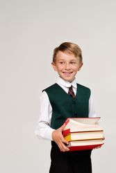 Portrait handsome preteen schoolboy in uniform in front of plain background