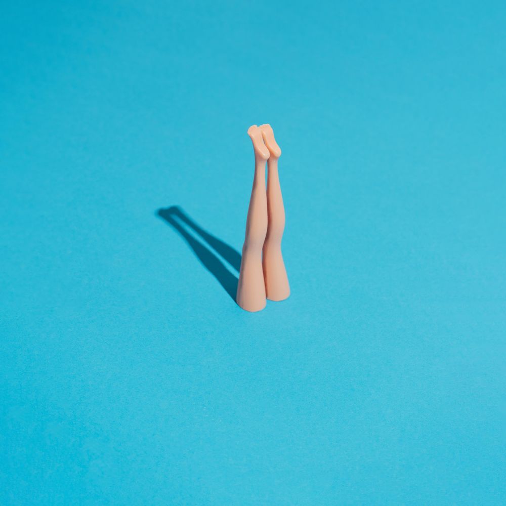 Doll legs sticking upright from blue background with shadow