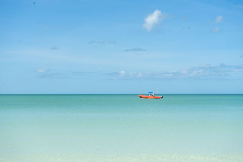 Orange boat in sea under blue sky