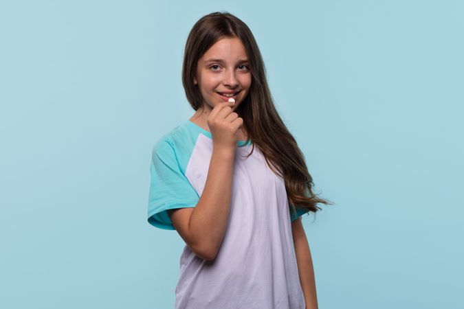 Girl smiles while holding white pill near mouth