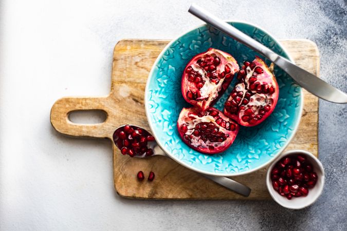 Teal bowl of open pomegranate with knife