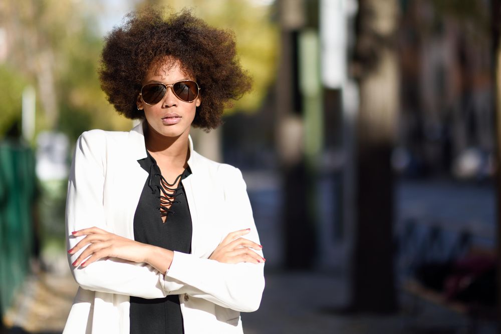 Female in aviator sunglasses and blazer standing in the sun