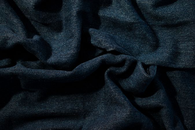Close up detail crumpled wavy Navy blue jeans fabric background texture.