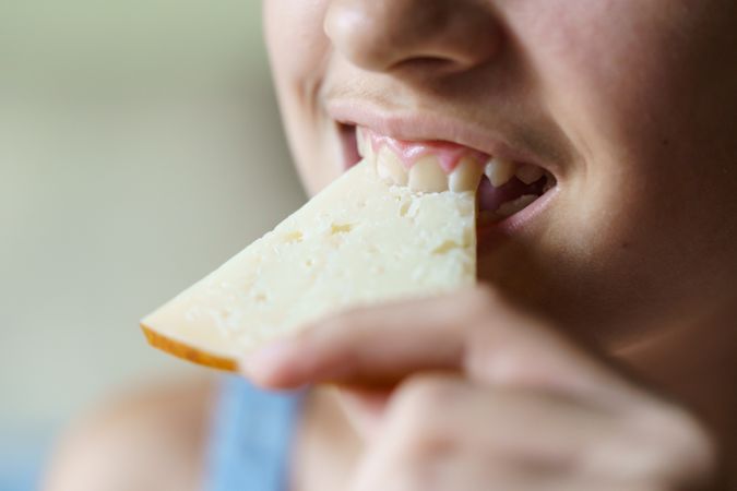 Girl biting into cheese slice