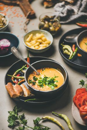 Yellow lentil soup bowl, bread, vegetable garnishes, selective focus, vertical composition