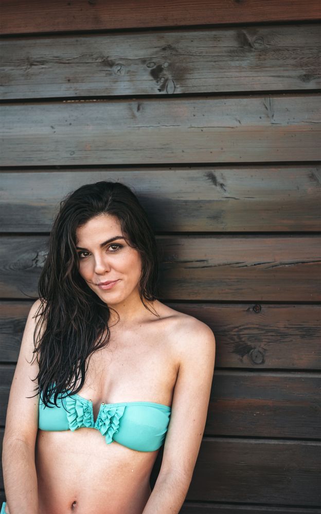 Young woman posing by wooden wall