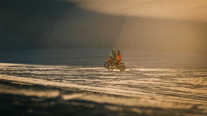 Dirt bikers racing motorcycles in desert