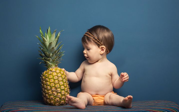 Happy baby playing with a pineapple