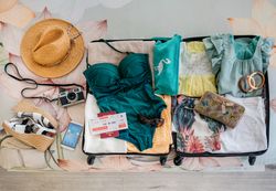 Open woman suitcase prepared for summer vacation