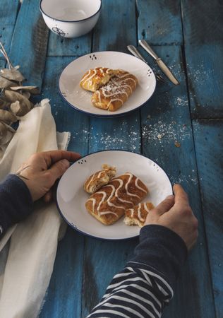 Faceless person taking sweet roll from rustic table