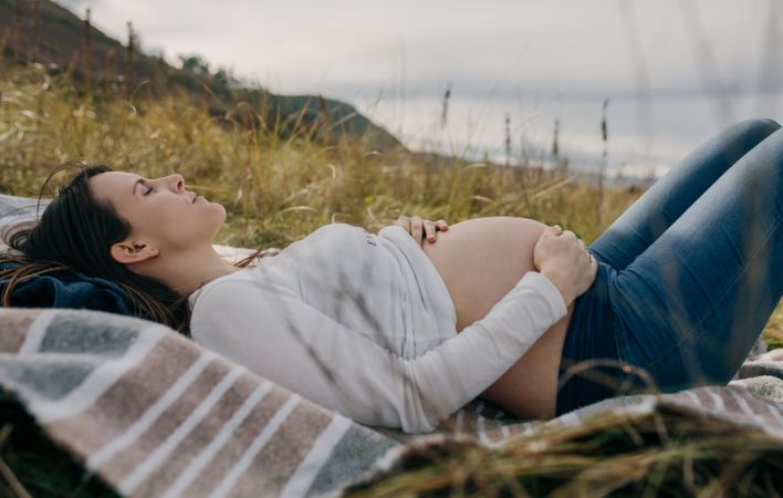 Pregnant woman caressing her tummy sleeping outside