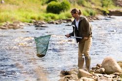 Female Fisherman Lifting Net from River