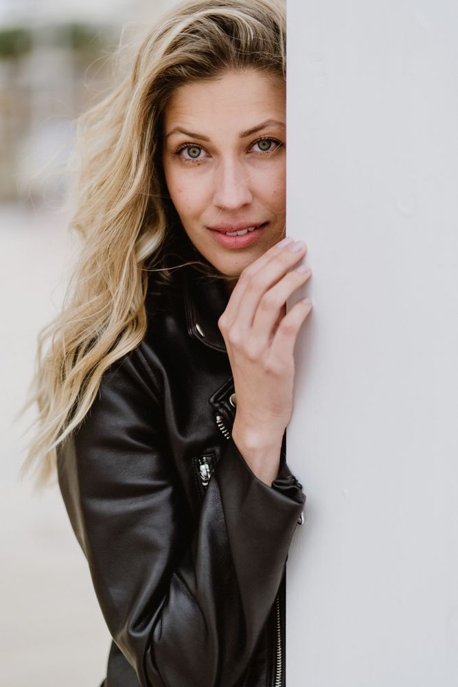 Charming tender woman standing behind white wall