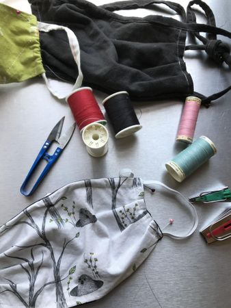 Flatlay of fabric face masks, scissors and thread for home sewing