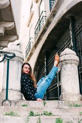 Young person sitting between pillars on street