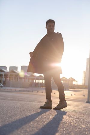 Black man standing outdoors with sunsetting behind him