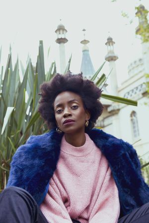 Woman in pink shirt and blue fur coat sitting outdoor