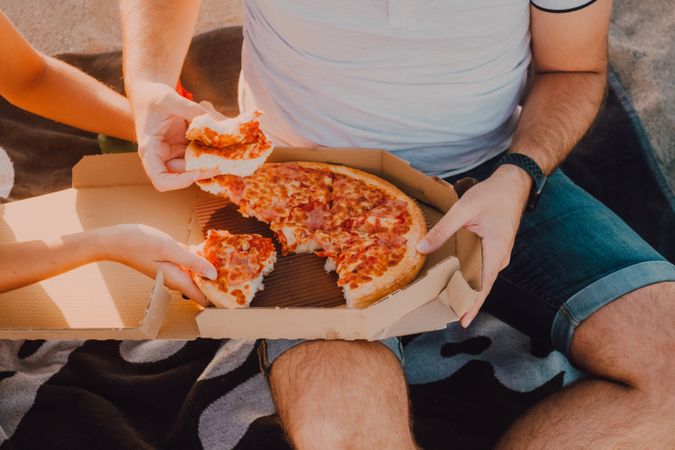 unrecognizable Lovely couple eating pizza together at sandy beach