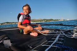 Cheerful boy sitting on boat and looking away in sea