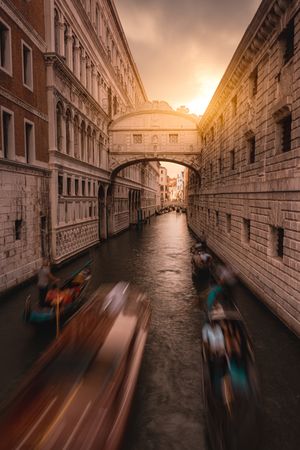 Gondolas sailing along canal between city buildings