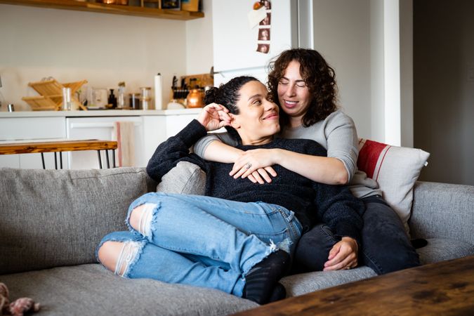 Relaxed female couple holding each other in living room