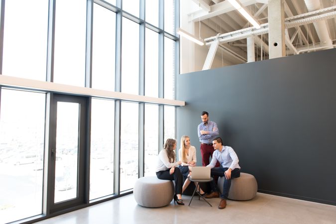 Stylish coworkers gathering around laptop in office