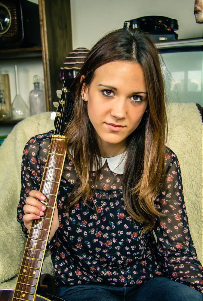 Young hipster female with acoustic guitar at home