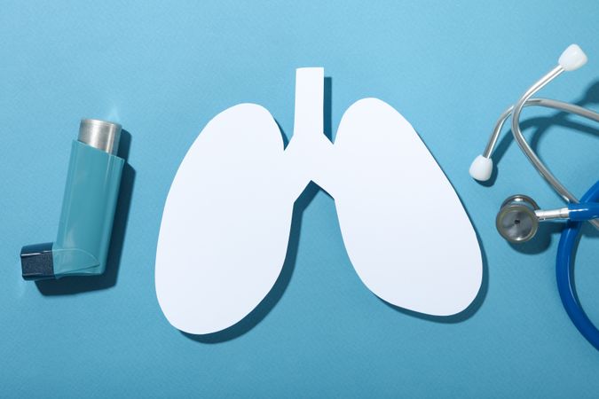 Lungs, inhaler, and stethoscope on blue background, asthma concept
