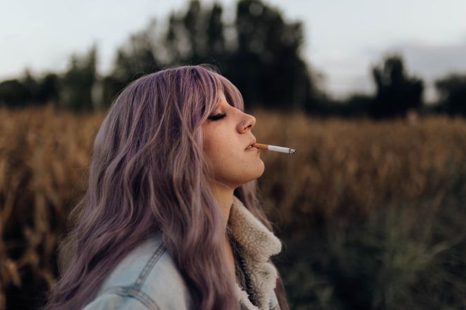 Smoking trendy woman in autumn nature
