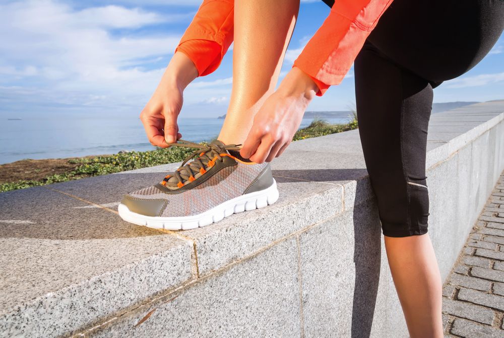 Fit woman tying trainers before work out on the beach