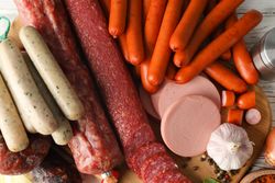 Close up of variety of cured meats and bulb of garlic on kitchen board