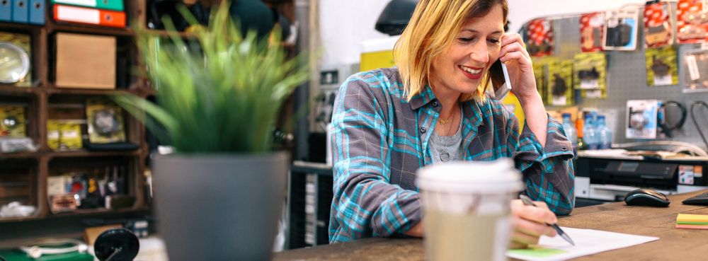 Smiling blonde young woman talking by cellphone in a store.