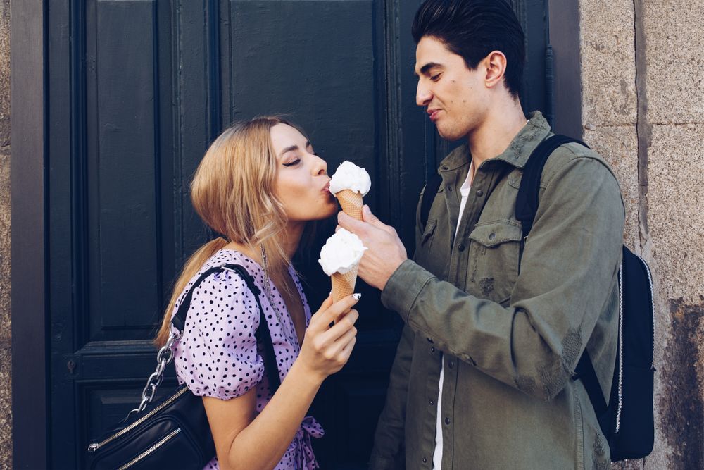 Happy couple feeding each other by ice cream